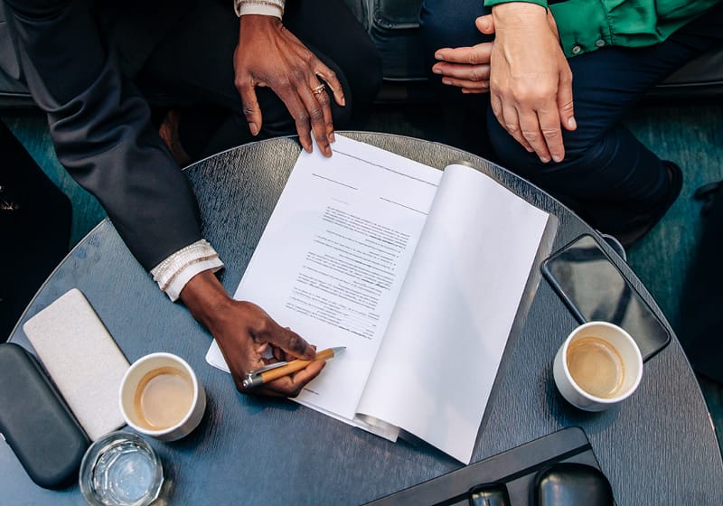 contract on a table with hands pointing to parts of the contract